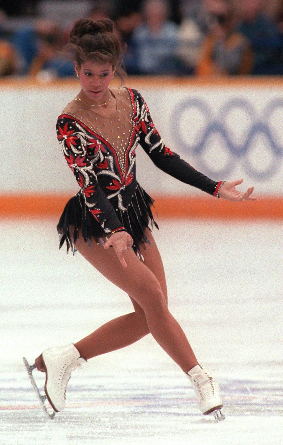 <p>'As we got into the '80s and '90s and 2000s, costumes really became a character in the performance,' Weir says. This is illustrated by American skater Debi Thomas's red and black costume with a rhinestone embellished mesh neckline and silver accents. By the '80s rhinestones were a full-fledged phenomenon and were used much more frequently than in past decades. </p><p>The beauty trends of the '80s, such as big hair and bright eyeshadow, also found their way into the Olympics. After the 1988 Olympics, strict clothing rules were passed because Russian skater <a rel="nofollow noopener" href="https://www.bostonglobe.com/lifestyle/style/2014/01/11/the-ice-rink-becomes-runway-for-female-figure-skaters/ZfSFpCEEKGGPrwzAcvnGRN/story.html" target="_blank" data-ylk="slk:Katarina Witt;elm:context_link;itc:0;sec:content-canvas" class="link ">Katarina Witt</a> opted for strategically-placed feathers instead of a full skirt to compete, and it was considered against the rules to wear a unitard or pants until the rule was <a rel="nofollow noopener" href="http://www.cosmopolitan.com/style-beauty/fashion/a19764/ice-skating-costume-facts/" target="_blank" data-ylk="slk:repealed in 2006.;elm:context_link;itc:0;sec:content-canvas" class="link ">repealed in 2006.</a></p>