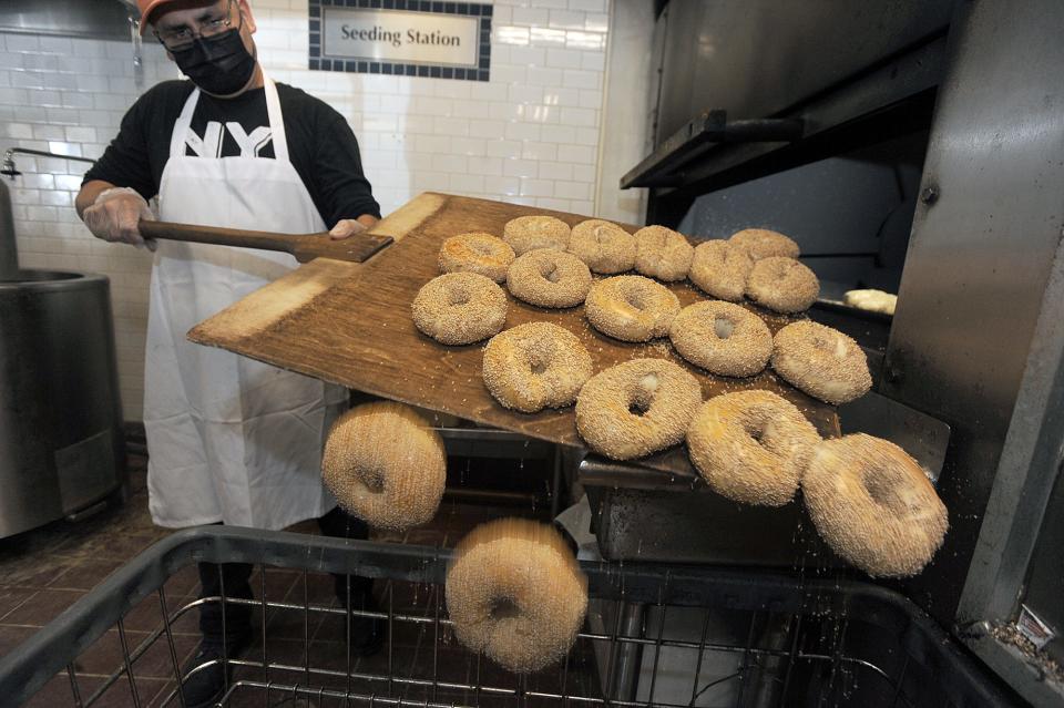 NY Bagel Factory baker Enrique Villanueva pulls sesame bagels from the oven, June 14, 2022.