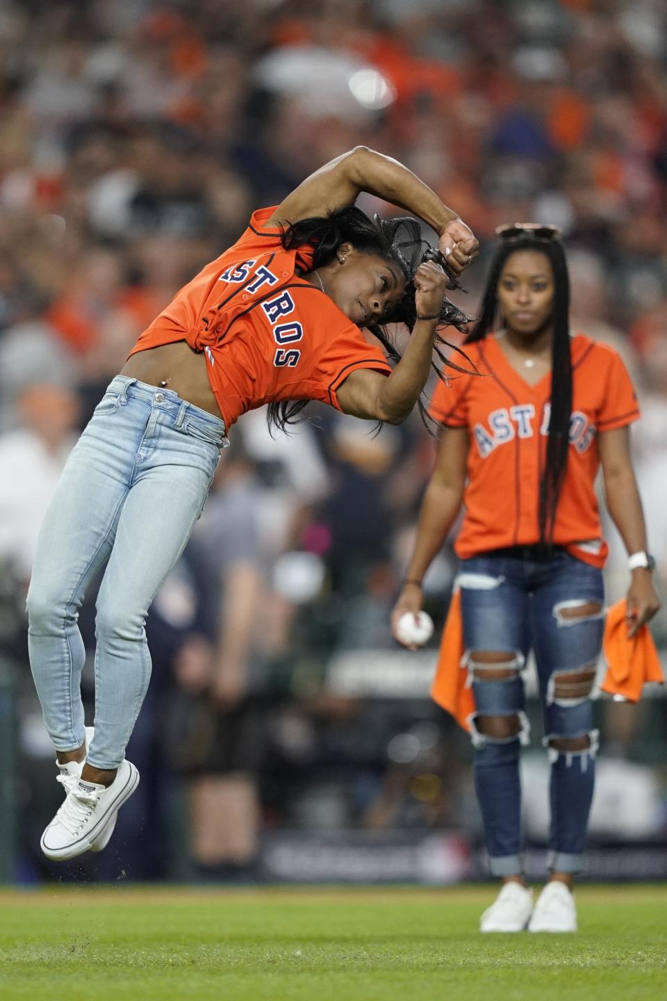 Gymnast Simone Biles does a flip before throwing the ceremonial first pitch before Game 2 of the baseball World Series between the Houston Astros and the Washington Nationals Wednesday, Oct. 23, 2019, in Houston. (AP Photo/David J. Phillip)