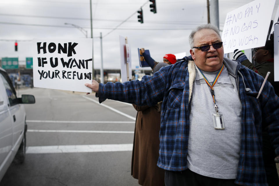 In this Jan. 10, 2019, photo, Will Kohler, an IRS tax examiner, holds a protest sign as union members and other federal employees rally to call for an end to the partial government shutdown outside the IRS site, in Covington, Ky. Kohler applied for unemployment after getting furloughed but said his application is in limbo because the Treasury Department office that needs to verify his claim is closed as a result of the shutdown. (AP Photo/John Minchillo)