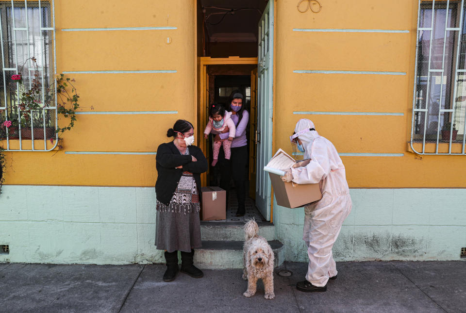 Un trabajador de la ciudad, vestido con ropa protectora, entrega una caja de comida durante una cuarentena obligatoria ordenada por el gobierno en medio de la pandemia del coronavirus en Santiago de Chile, el viernes 22 de mayo de 2020. (Foto AP/Esteban Félix)