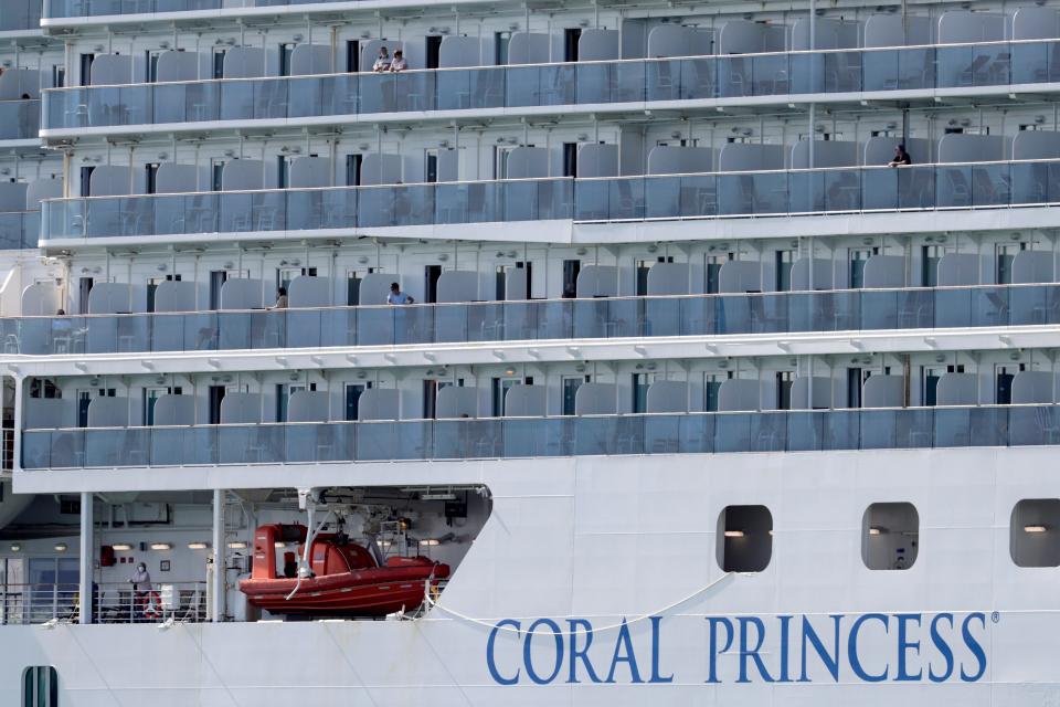 People look out from their balconies on the Coral Princess cruise ship as it is docked at PortMiami on April 4, 2020. 