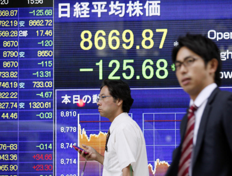 People walk by an electronic stock board outsdie a securities firm in Tokyo, Friday, July 20, 2012. Asian stock markets wavered Friday as weak U.S. data kept sentiment in check despite continued hopes for new stimulus measures in major economies. Japan's Nikkei 225 was down 0.9 percent at 8,717.60. (AP Photo/Koji Sasahara)