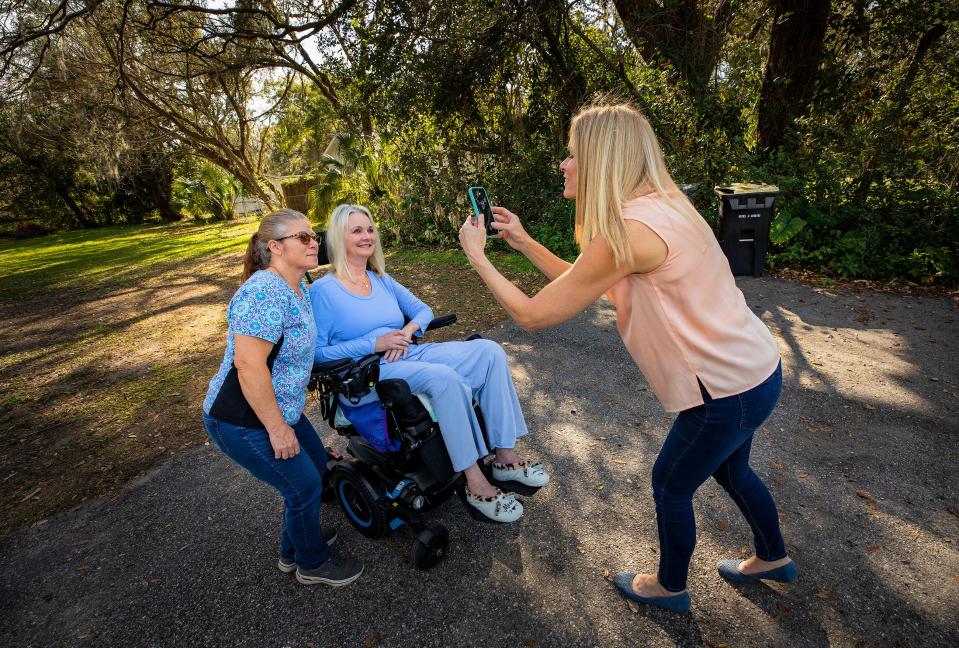 Laura Carpenter takes a photo of her friend, Laura Pinner, and one of Pinner's caregivers, Rhonda Batts, in February at the Pinner home in South Lakeland. Pinner, who was diagnosed in 2021 with ALS, died Friday morning.