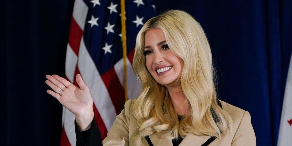 Ivanka Trump waving her hand, standing in front of American flag.