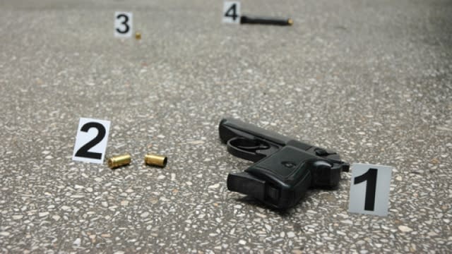 Stock photo of a handgun and shell casings lying on a road.