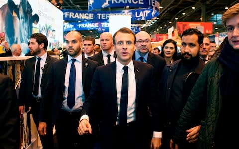 In this file picture taken on February 24, 2018, French President Emmanuel Macron (C), flanked by security officer Alexandre Benalla (2ndR), visits the 55th International Agriculture Fair (Salon de l'Agriculture) at the Porte de Versailles exhibition center in Paris - Credit: AFP