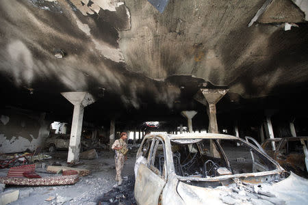 A security guard looks at a damaged car during a visit by human rights activists to a community hall that was struck by an airstrike during a funeral on October 8, in Sanaa, Yemen, October 16, 2016. REUTERS/Mohamed al-Sayaghi