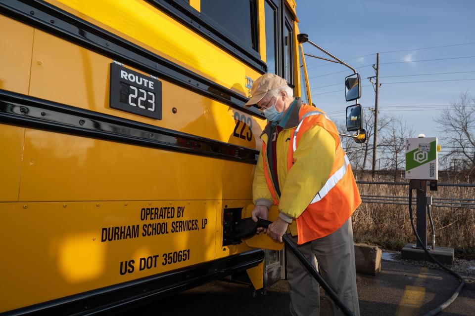 Bus driver Charlie Bogg charges an electric school bus at Ann Arbor's Pioneer High School.