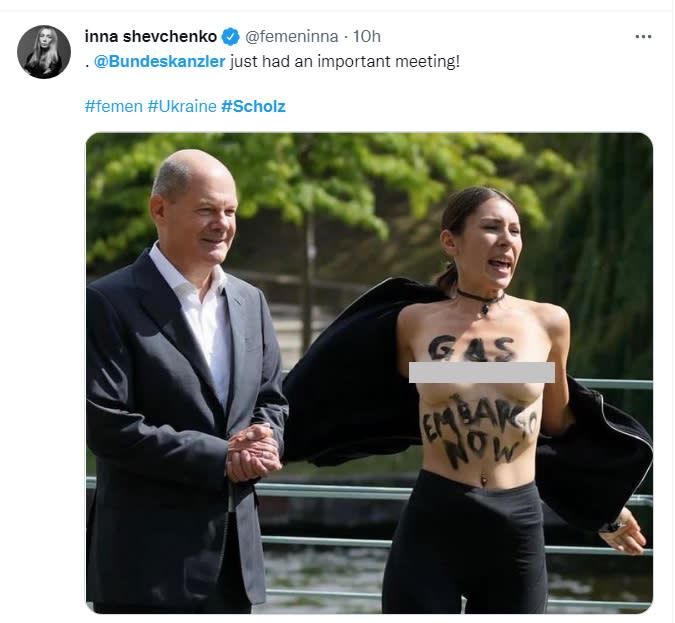 德國總理蕭茲（左）21日在聯邦總理府的開放日與民眾合照時，合照的女性突然脫去上衣，露出「Gas Embargo Now」標語，傳遍國際。   圖：翻攝自inna shevchenko推特