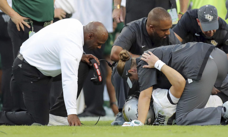 South Florida coach Charlie Strong comforts Central Florida quarterback McKenzie Milton, after injuring his right leg on Nov. 23, 2018, in Tampa, Fla. (AP Photo/Mike Carlson)