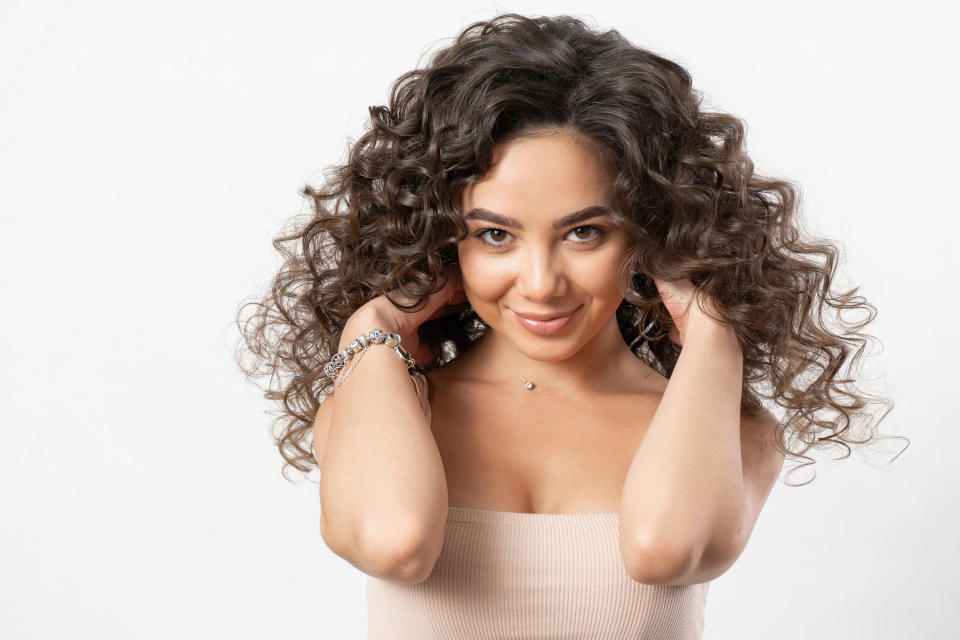 A smiling woman touching her curls