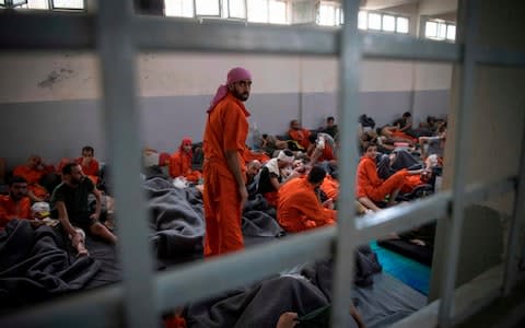 Men, allegedly affiliated with the Islamic State group, sit on the floor in a prison in the northeastern Syrian city of Hasakeh - Credit: AFP