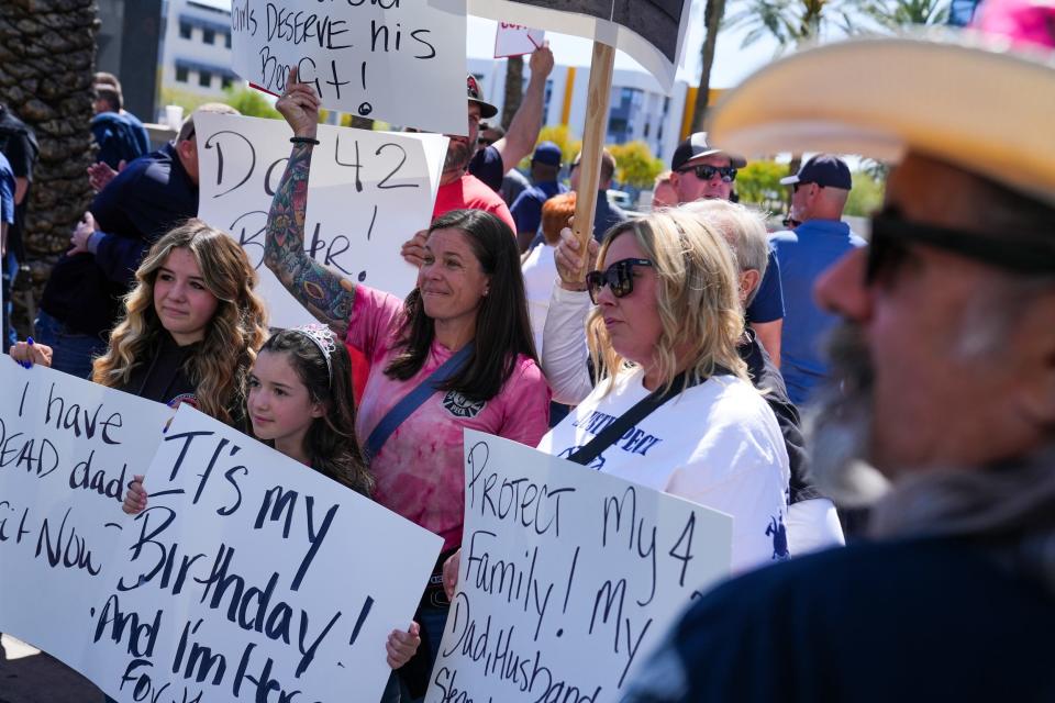 Marley Peck, 14, Harper Peck, 11, (center), Erin Peck and Kendal Dold protest for Goodyear firefighters Gilbert Aguirre and Austin Peck outside the CopperPoint Insurance Companies building on April 5, 2023, in Phoenix. Austin died from cancer he got working in the same crew. Aguirre was diagnosed with chronic myeloid leukemia, a work-related cancer, in 2015. The insurance company has repeatedly declined Aguirre's workers' compensation claim, arguing he failed to prove he got cancer on the job.