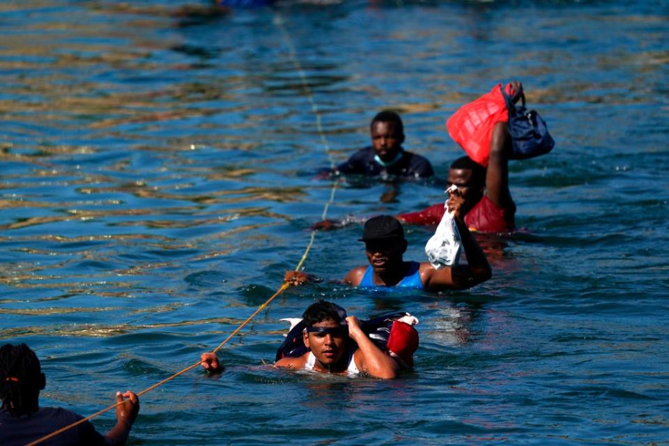 Migrants, many from Haiti, wade across the Rio Grande from Del Rio, Texas, to return to Ciudad Acuna, Mexico, Tuesday, 21 September 2021, to avoid deportation from the US (AP)