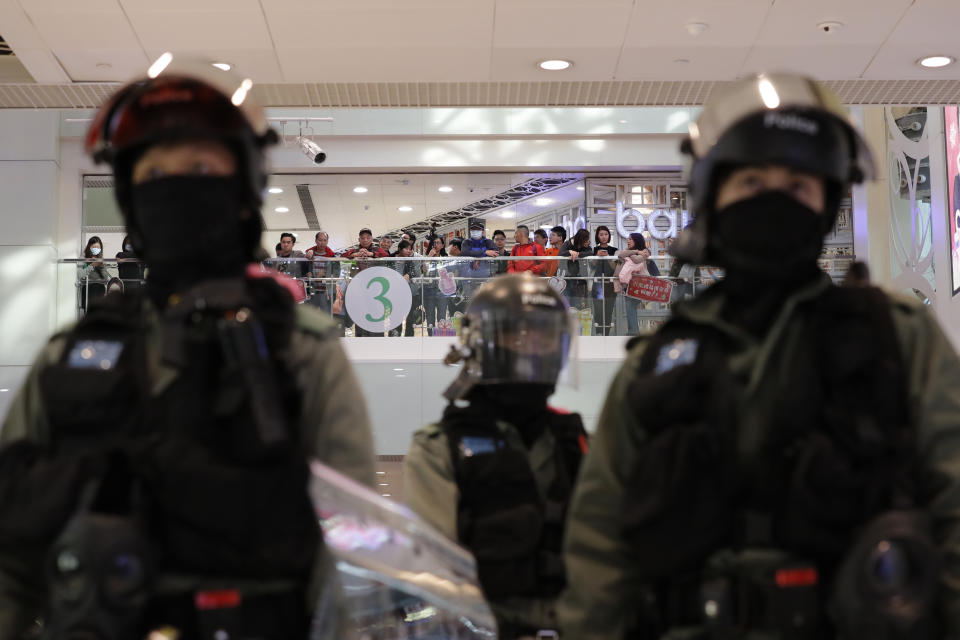 Shoppers watch as riot police gather at a shopping mall popular with traders from mainland China near the Chinese border in Hong Kong, Saturday, Dec. 28, 2019. Protesters shouting "Liberate Hong Kong!" marched through a shopping mall Saturday to demand that mainland Chinese traders leave the territory in a fresh weekend of anti-government tension. (AP Photo/Lee Jin-man)