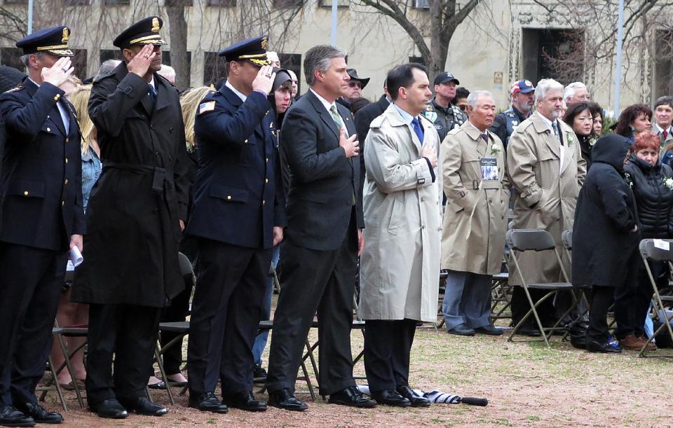 Wisconsin Gov. Scott Walker, fifth from left, salutes the U.S. flag Wednesday, May 7, 2014, during a memorial event in Milwaukee for fallen law enforcement officers. Walker, who scored a major court victory a day earlier when a judge halted an investigation into his 2012 recall campaign, said he is glad the case seems to be approaching an end so he can return to the business of governing. (AP Photo/Dinesh Ramde)