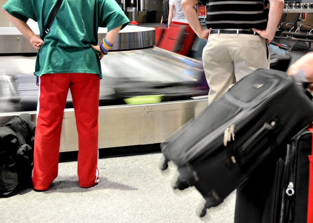 Passengers wait for baggage at airport carousel.