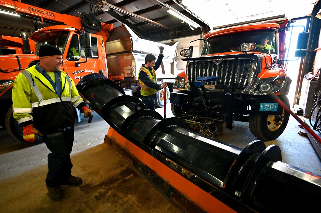 Nathan Boulanger, center, guides plow driver Alex Flynn as he and fellow Douglas Highway Department employee Mark Towle, left, work together to attach a plow to the truck Monday.