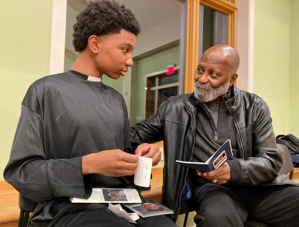 Ryan Harris, 15, dressed in a long black cassock or priest vestment, portrayed Augustus Tolton, one of six Black Catholics up for sainthood by the Vatican. Harris stamps a "passport" of an audience member as part of a program held at St. Francis of Assisi Parish honoring the six individuals on Nov. 17.