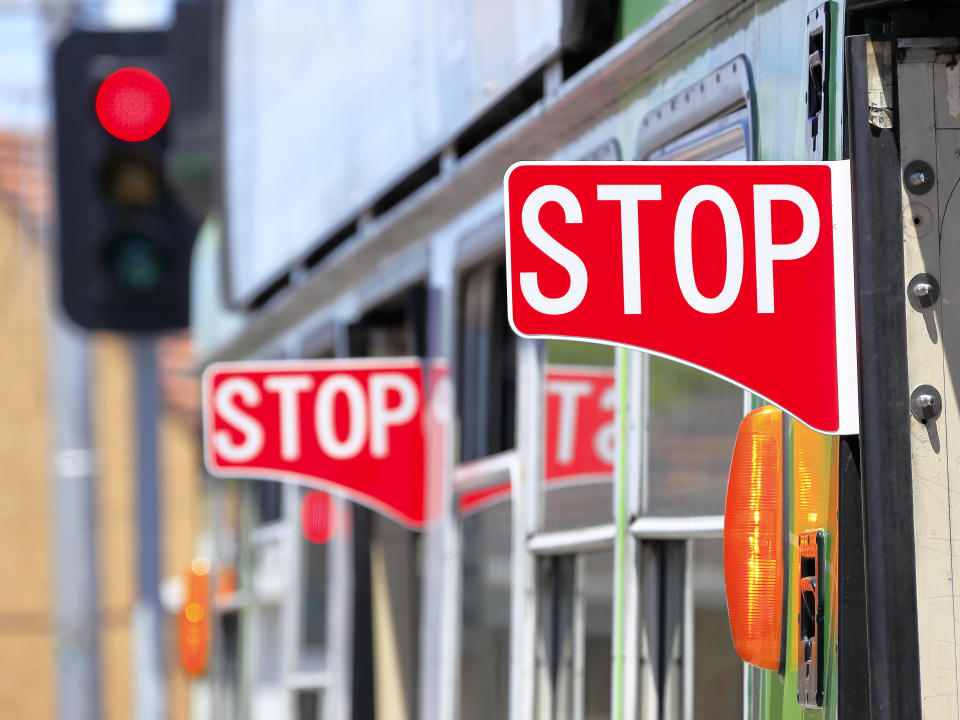 Multiple red stop signs and warning indicators on the side of a Yarra Trams Melbourne Z-class tram with red traffic light in the background.