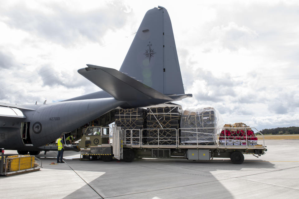 In this photo provided by the New Zealand Defence Force, a Royal New Zealand Air Force C-130 Hercules is loaded before it leaves an airbase in Auckland, Thursday, Jan. 20, 2022, flying to Tonga with aid. The first flight carrying fresh water and other aid to Tonga was finally able to leave Thursday after the Pacific nation's main airport runway was cleared of ash left by a huge volcanic eruption. (CPL Dillon Anderson/New Zealand Defence Force via AP)