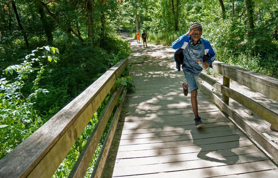 Jorden Johnson runs across a bridge during a hike Thursday, June 30, 2022 at Fort Harrison State Park. Share LT students from Belzer Middle School and Fall Creek Valley Middle School canoed, fished, hiked and did a creek study with Camptown.