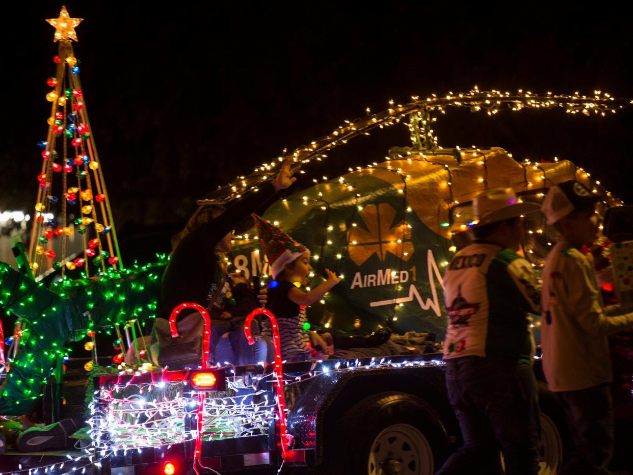 A little girl waves from a parade float decorated as Shannon Medical Center's AirMed1 during the Concho Christmas Celebration parade, Saturday, Dec. 4, 2021.