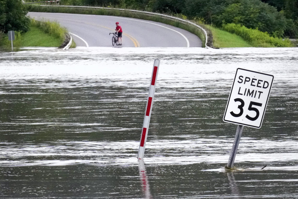 A cyclist pauses to look at a water-filled roadway.