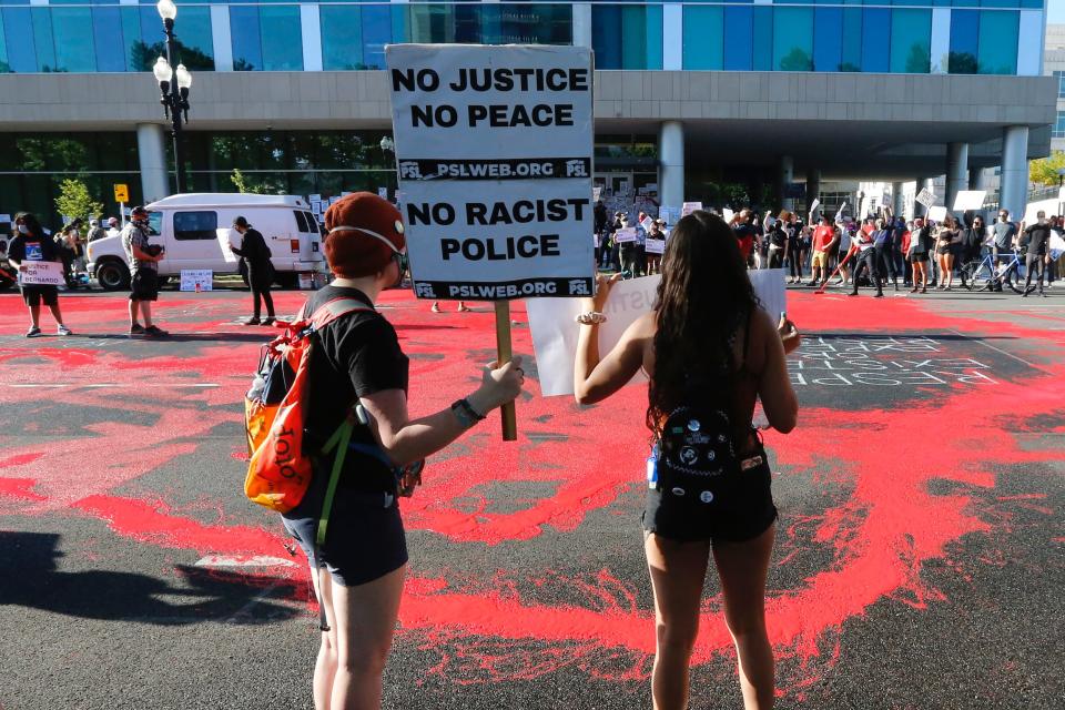 In this July 9, 2020, file photo, protesters gather in front of district attorney's office in Salt Lake City, where demonstrators covered the street in red paint