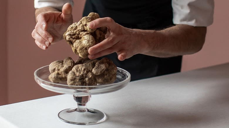 man holding white truffles on a cake stand 