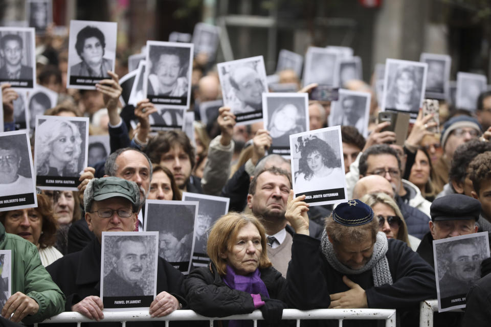 People hold up pictures of people who died during the bombing at the AMIA Jewish center that killed 85 people on the 25th anniversary of the attack in Buenos Aires, Argentina, Thursday, July 18, 2019. (AP Photo/Natacha Pisarenko)