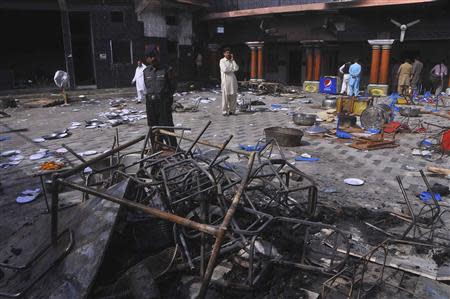 A security official and members of the Hindu community stand inside a temple that was attacked on Saturday night, in Larkana, southern Pakistan's Sindh province, March 16, 2014. REUTERS/ Faheem Soormro