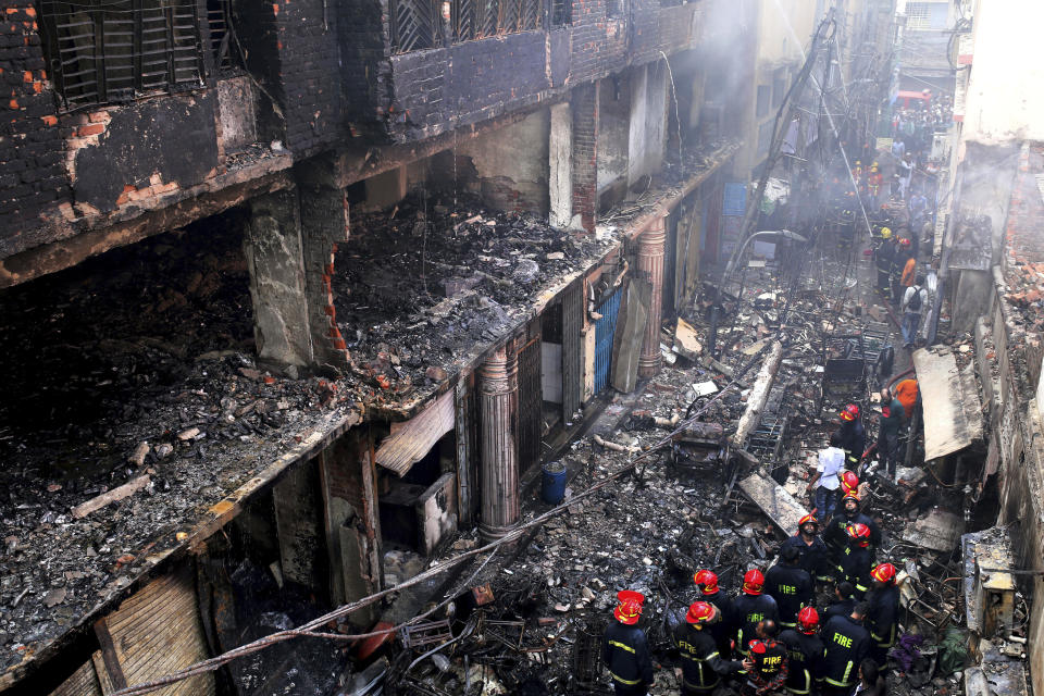 In this, Thursday, Feb. 21, 2019 file photo, locals and firefighters gather around buildings that caught fire late Wednesday, Feb. 20 in Dhaka, Bangladesh. After more than 1,100 people died when a garment factory complex collapsed in Dhaka, Bangladesh authorities imposed more stringent safety rules. But corruption and lax enforcement have resulted in many more deaths linked to safety lapses since the 2013 Rana Plaza disaster, including a fire Thursday in an illegally-constructed high-rise office building that killed at least 25 people and left dozens more injured. (AP Photo/Rehman Asad, File)