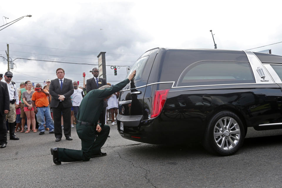 <p>East Baton Rouge Sheriff Sid J. Gautreaux, III kneels and places his hand on the casket of deputy Brad Garafola, after it was transferred from carriage to hearse, at the scene where Garafola and two Baton Rouge police were killed, in Baton Rouge, La., July 23, 2016.(Photo: Gerald Herbert/AP</p>