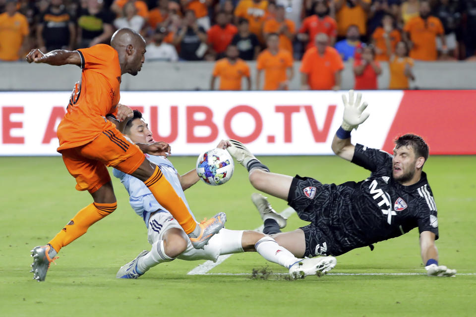 Houston Dynamo midfielder Fafa Picault, left, shoots on goal as FC Dallas defender Marco Farfan, center, and goalkeeper Maarten Paes, right, successfully defend the goal during the second half of an MLS soccer match Saturday, July 9, 2022, in Houston. Farfan was injured on the play and was taken from the pitch. (AP Photo/Michael Wyke)