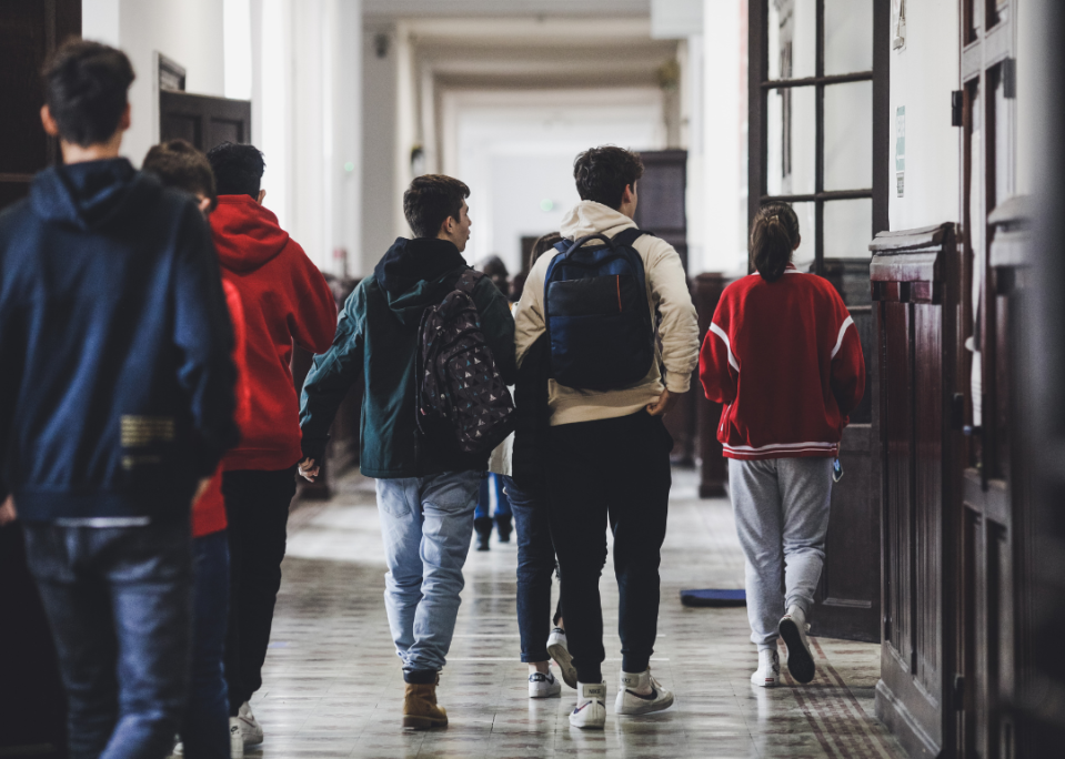 Students walking down a hallway with their backs facing the camera.