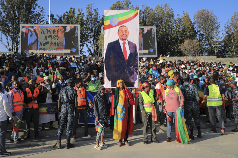 People gather under a placard showing Prime Minister Abiy Ahmed at a rally organized by local authorities to show support for the Ethiopian National Defense Force (ENDF), at Meskel square in downtown Addis Ababa, Ethiopia Sunday, Nov. 7, 2021. (AP Photo)