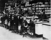 <p>A group of children stand in line as they wait to collect a loaf of bread from a local shopkeeper during a coal strike.</p>