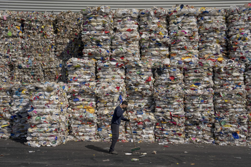 A GreenNet recycling plant employee cleans the ground next to piles of disposable plastic ready for export, in Atarot industrial zone, north of Jerusalem, Wednesday, Jan. 25, 2023. Israel's new government is in the process of repealing a new tax on single-use plastics. Ultra-Orthodox Jews, who have large families and use large quantities of disposable cups, plates and cutlery, say the tax unfairly targeted them. (AP Photo/Oded Balilty)