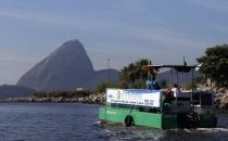 A garbage collecting boat in seen in front of the Sugar Loaf mountain at the Guanabara Bay in Rio de Janeiro March 12, 2014. According to the local media, the city of Rio de Janeiro continues to face criticism locally and abroad that the bodies of water it plans to use for competition in the 2016 Olympic Games are too polluted to host events. Untreated sewage and trash frequently find their way into the Atlantic waters of Copacabana Beach and Guanabara Bay - both future sites to events such as marathon swimming, sailing and triathlon events. The banner reads "Project Bay without garbage". Picture taken on March 12, 2014. REUTERS/Sergio Moraes (BRAZIL - Tags: ENVIRONMENT SPORT OLYMPICS)