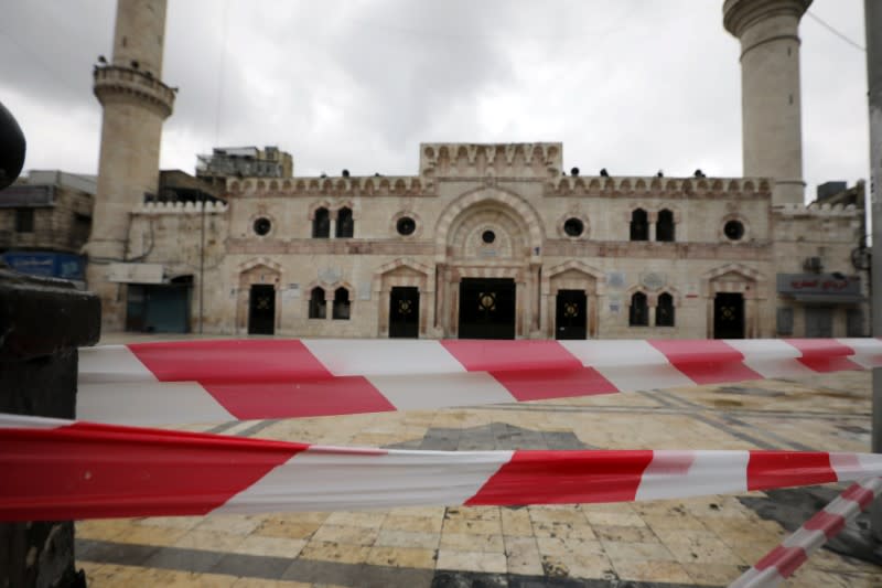 Plastic warning tape hangs in front of al Husseini mosque building after closing it to the worshippers amid concerns over the coronavirus disease (COVID-19) spread, in downtown Amman