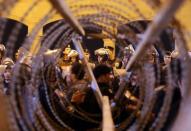 Policemen and soccer fans are seen through barbed wire as fans attempt to enter a stadium to watch a match, on the outskirts of Cairo February 8, 2015. REUTERS/Al Youm Al Saabi Newspaper