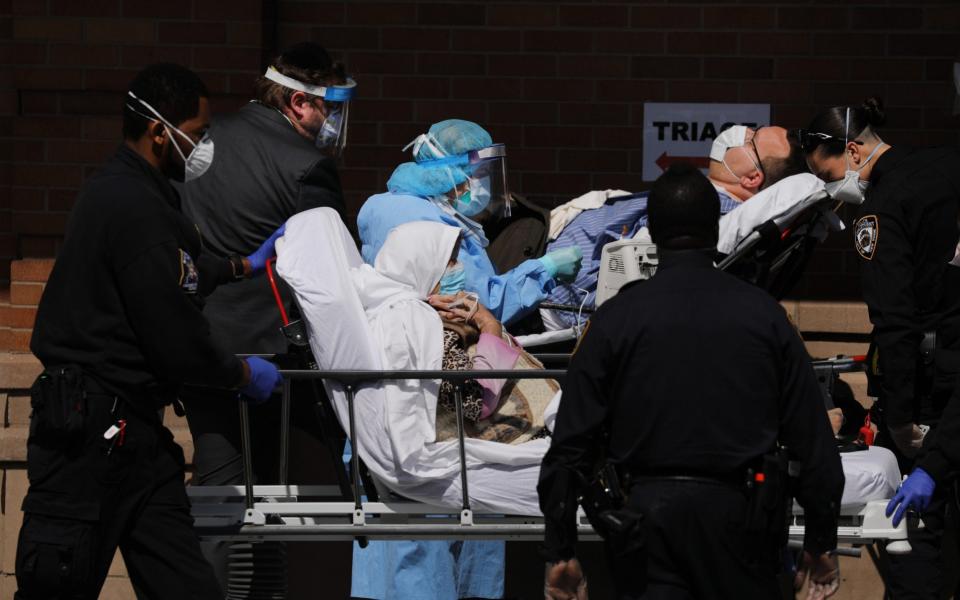 Medical workers work with numerous patients outside of a special coronavirus intake area at Maimonides Medical Center in the Brooklyn borough of New York City - Getty