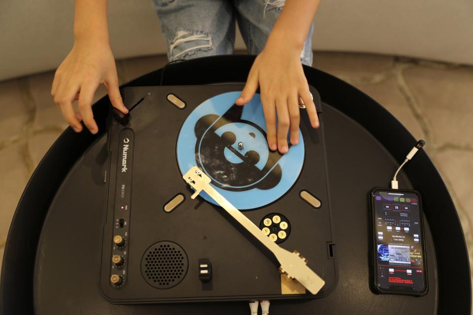 Michelle Rasul enjoys scratching her turntable in the lobby of her apartment building in Dubai, United Arab Emirates, Sunday, May 9, 2021. Rasul, a 9-year-old girl from Azerbaijan who lives in Dubai, is scratching her way to the top as a DJ after competing in the DMC World DJ Championship. (AP Photo/Kamran Jebreili)