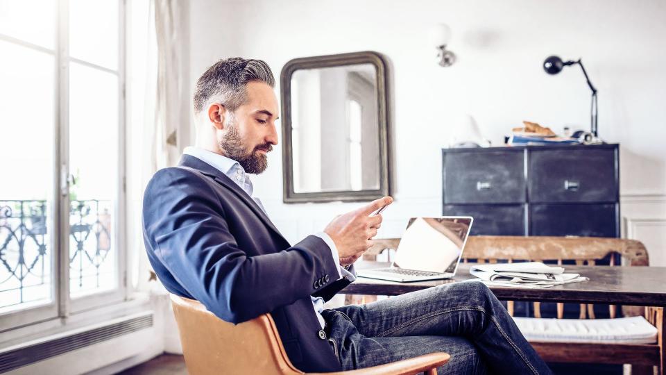 bearded business man reading on mobile in home office.