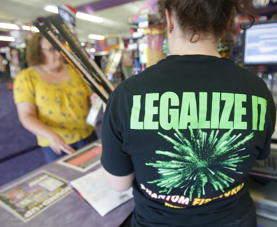 Rayna Keller, a lead cashier at Phantom Fireworks in southwest Canton, dons a "Legalize It" T-shirt as she works with customers earlier in June. Phantom Fireworks has been working to help legalize fireworks in Ohio for about a dozen years.