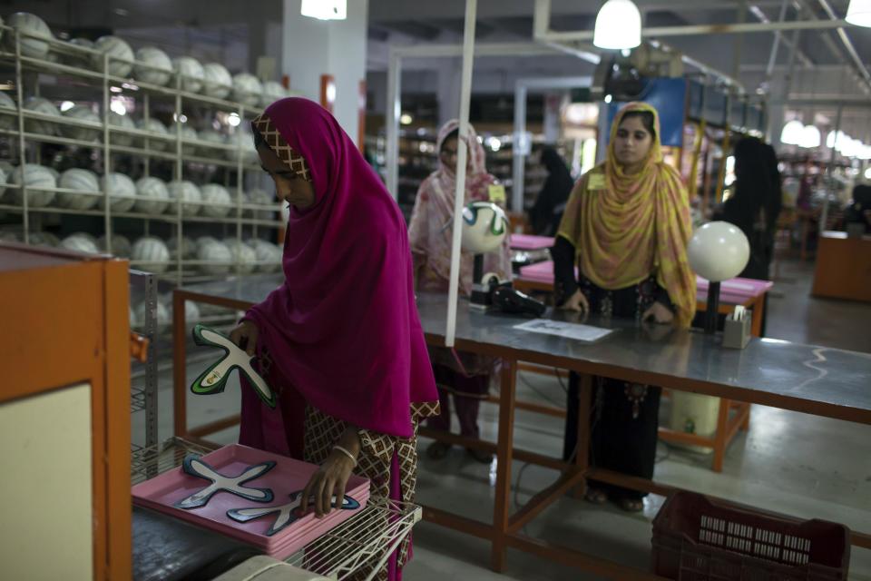 An employee collects ball panels from a machine inside the soccer ball factory that produces official match balls for 2014 World Cup in Brazil, in Sialkot, Punjab province