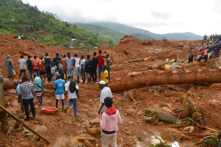Residents stand as rescue workers search for survivors after a mudslide in the mountain town of Regent, Sierra Leone August 14, 2017. REUTERS/Ernest Henry