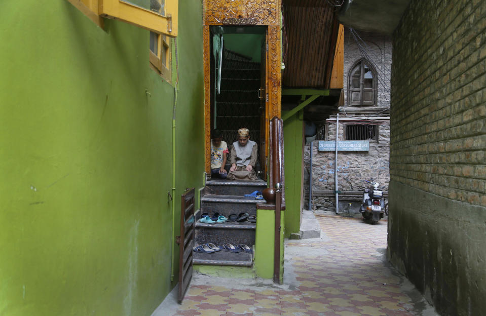 Kashmiri Muslim boys offer Friday prayers at the doorway of a local mosque in an alley during curfew like restrictions in Srinagar, India, Friday, Aug. 16, 2019. India's government assured the Supreme Court on Friday that the situation in disputed Kashmir is being reviewed daily and unprecedented security restrictions will be removed over the next few days, an attorney said after the court heard challenges to India's moves. (AP Photo/Mukhtar Khan)